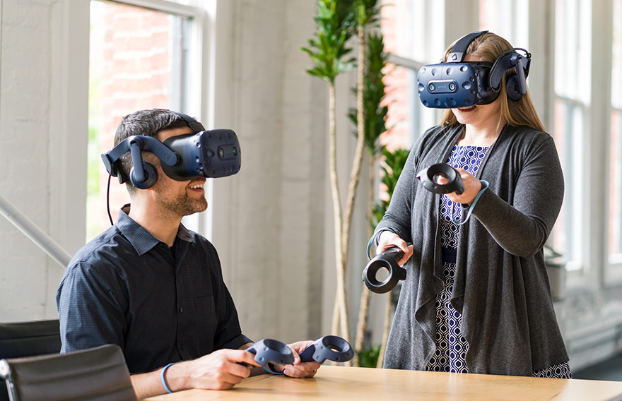 A man and woman using VIVE headsets in an office